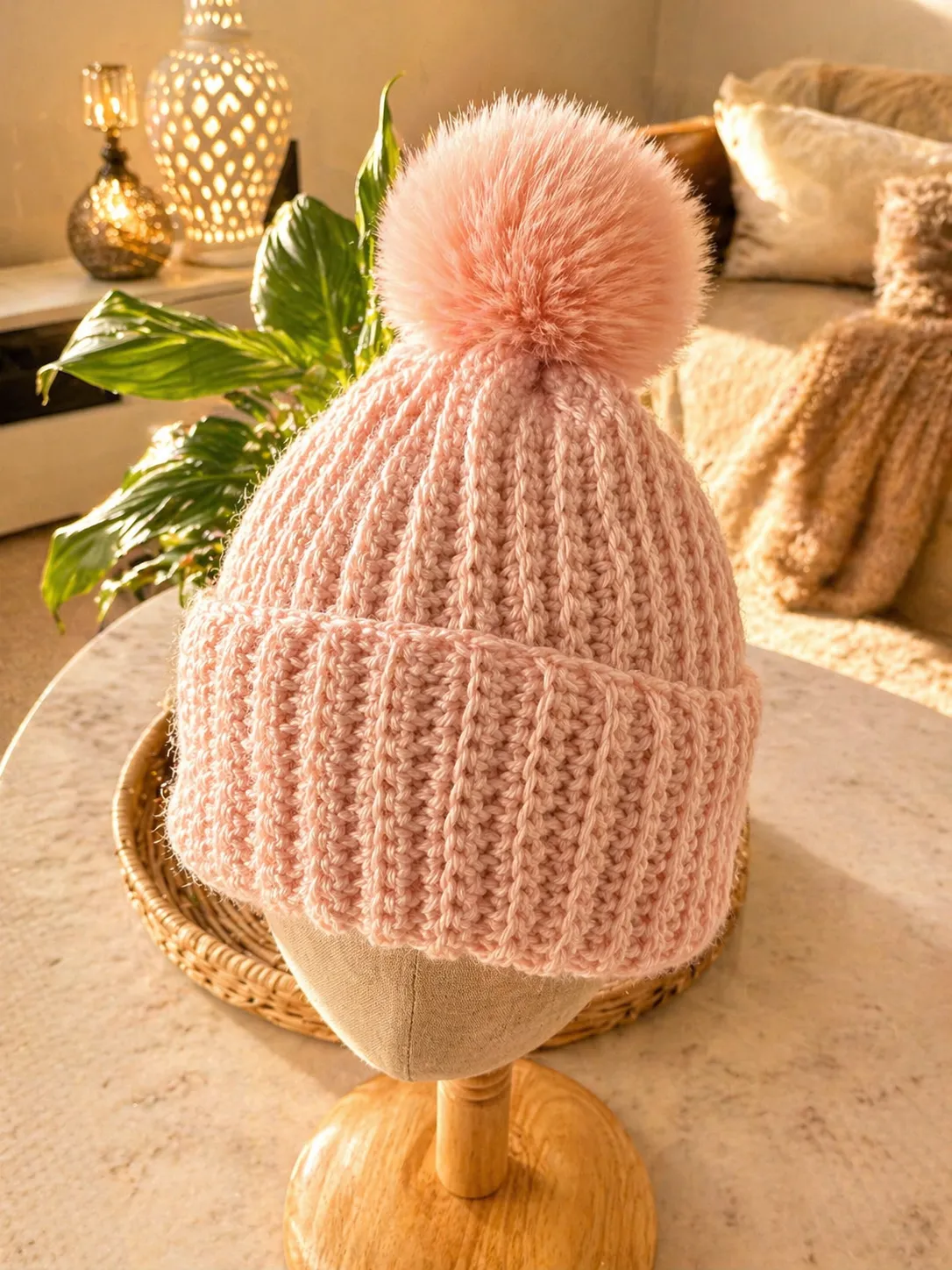 Hand-crocheted blush pink ribbed beanie with large fuzzy pom-pom