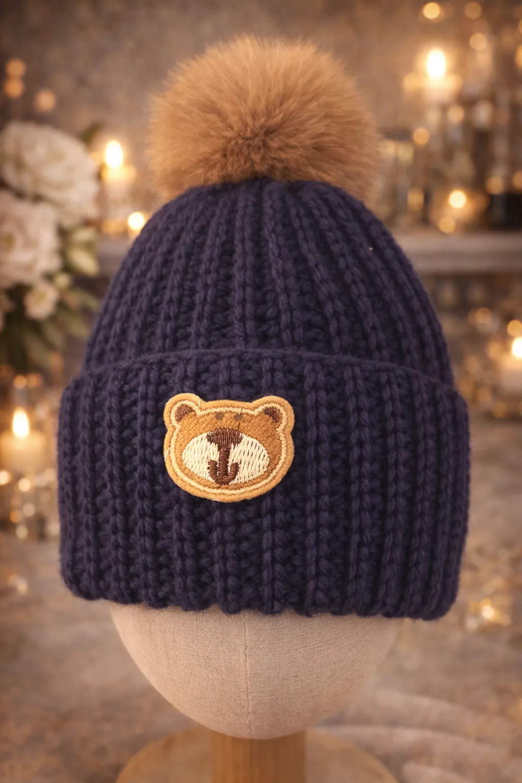 Deep-navy ribbed kids beanie with honey pom and embroidered bear face on the cuff.