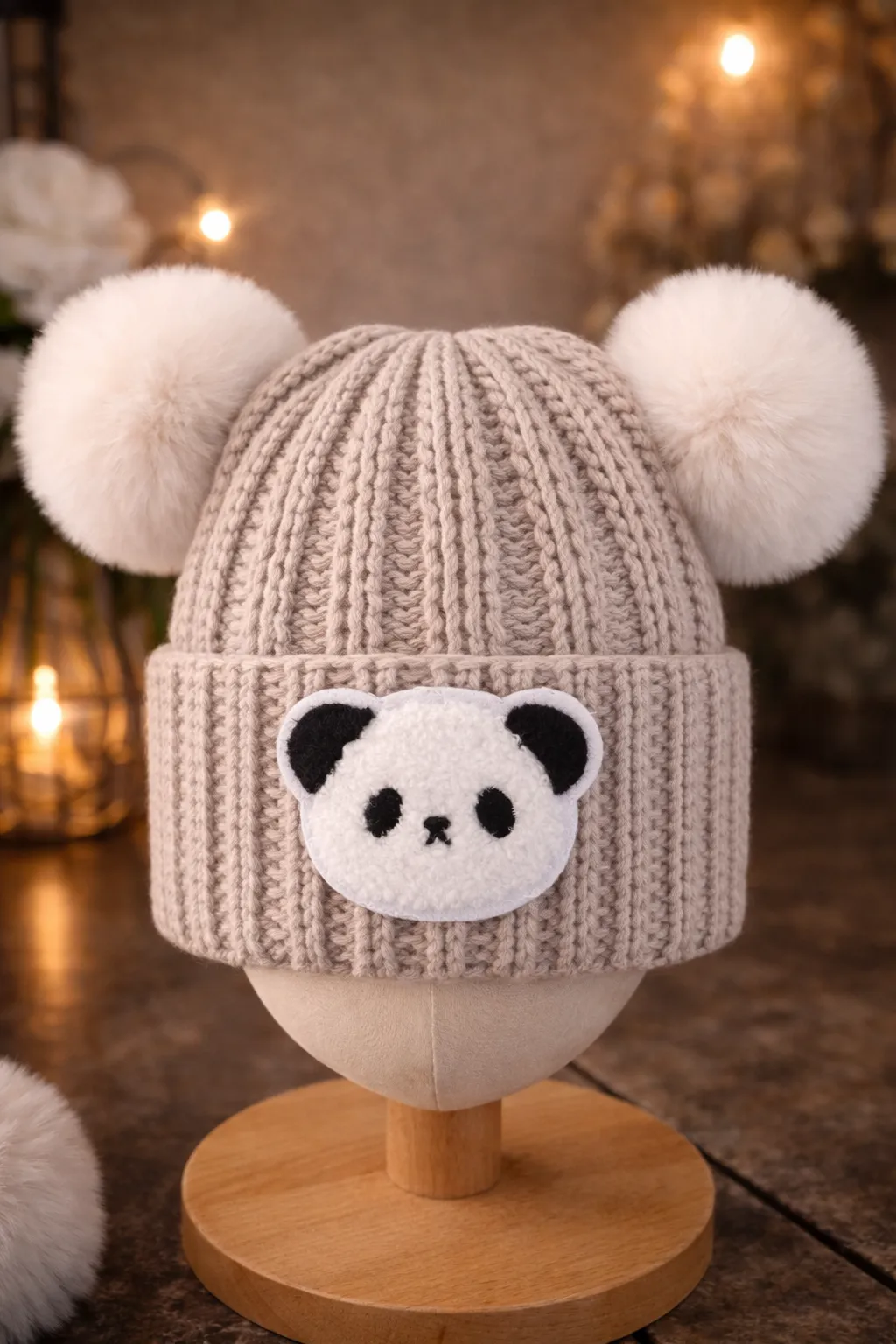 An oatmeal-coloured kids beanie with panda-ear crochet details and a matching pom.
