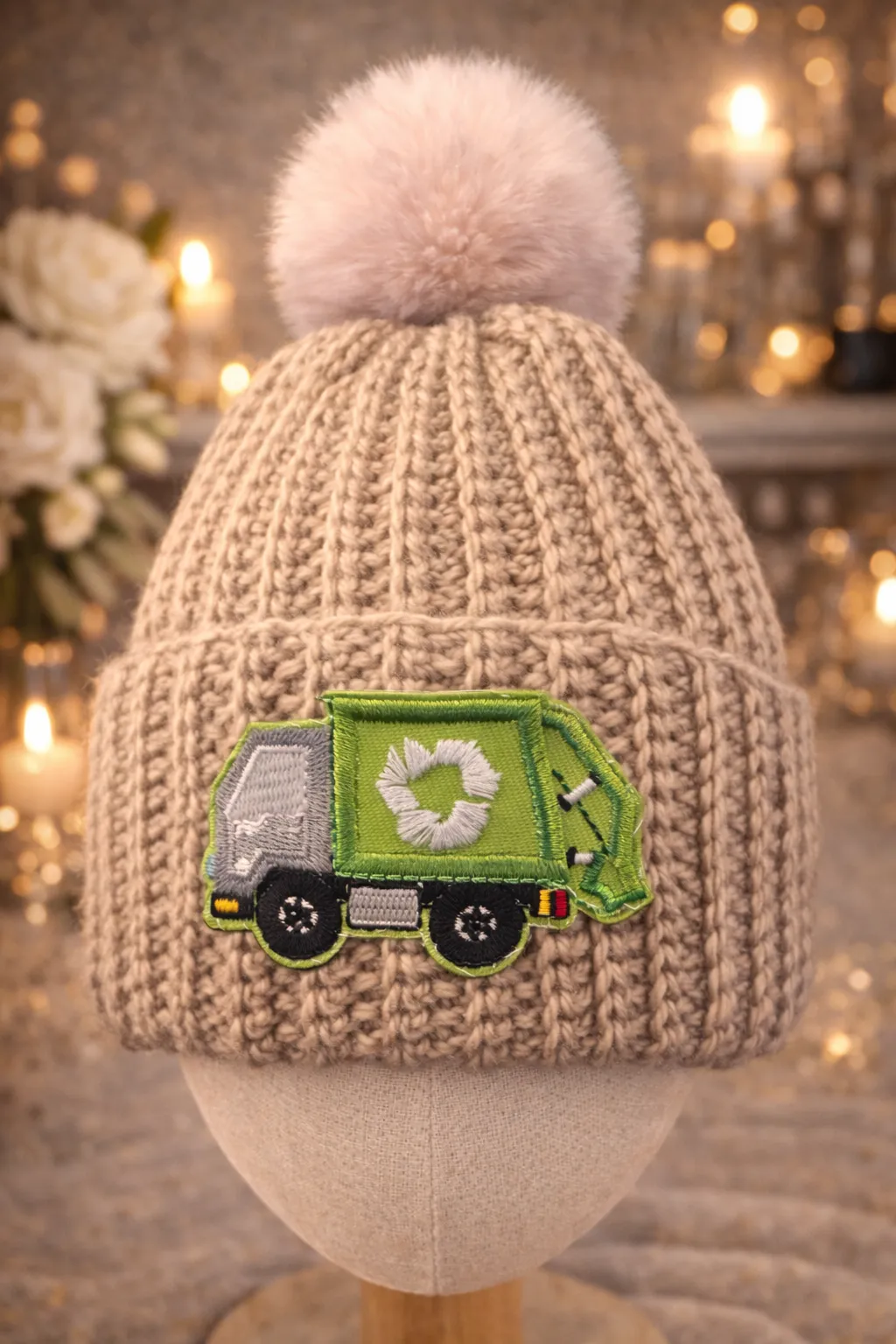 Oatmeal ribbed kids beanie with cream pom and green rubbish-truck patch.